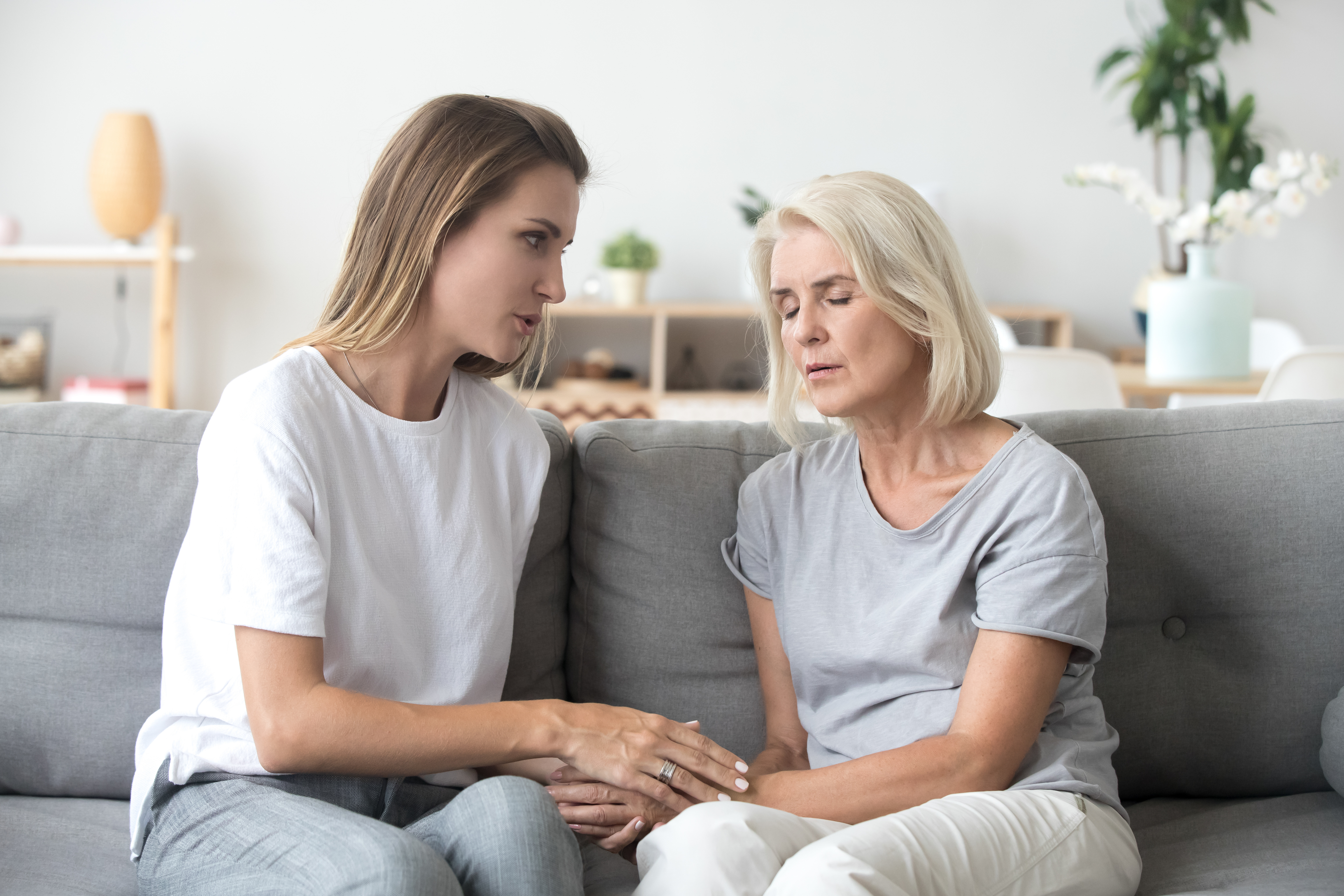 Adult daughter talking to sad old mother supporting upset woman